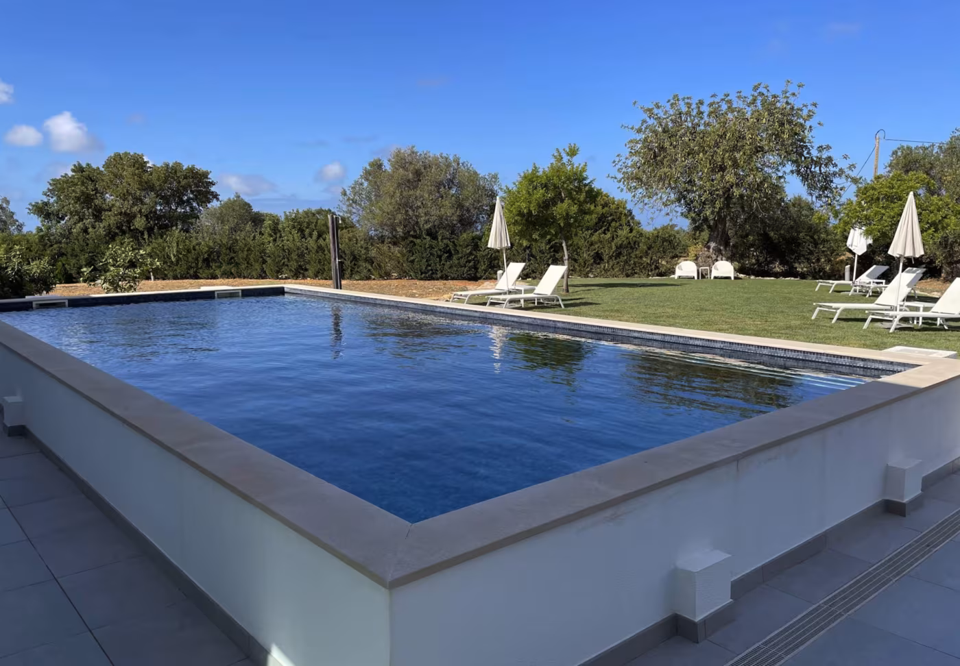 The pool at Mercedes Country House with sun loungers and umbrellas on the lawn
